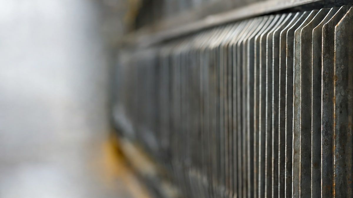An abstract study: repeated heat-exchanger fins, soft side light revealing depth and wear